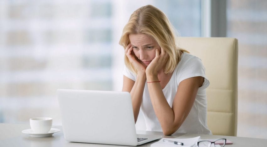 disheartened woman stares at laptop
