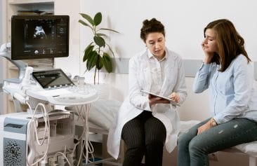 Doctor focusing on the customer experience by reviewing test results with a patient while sitting next to an ultrasound machine