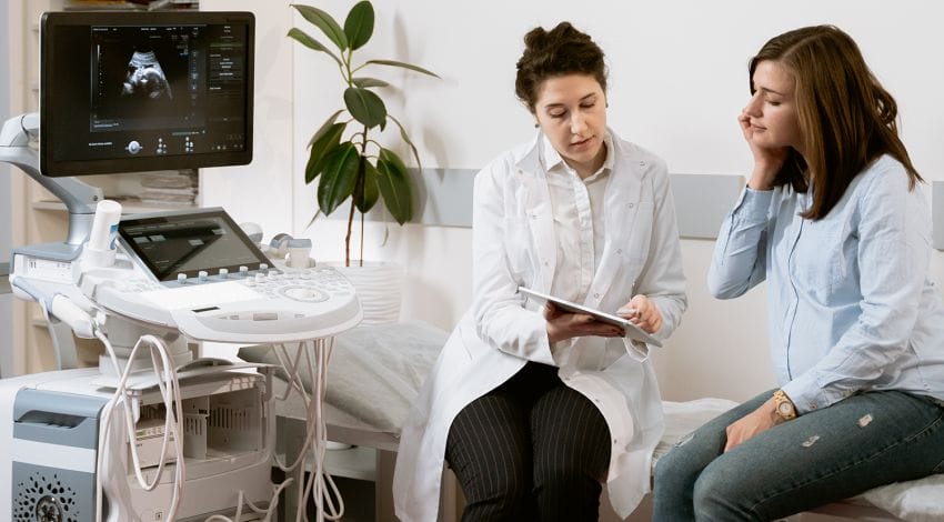 Doctor focusing on the customer experience by reviewing test results with a patient while sitting next to an ultrasound machine